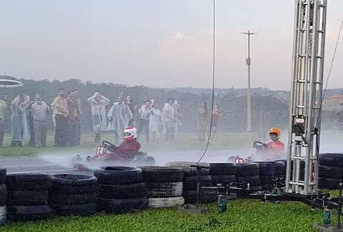 Gravação de cena de kart na chuva, com figurantes ao fundo